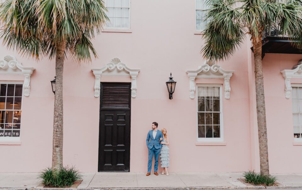 a man and woman standing on a sidewalk in front of a pink building. Photoshoot Locations by Bushel + Peck Photo